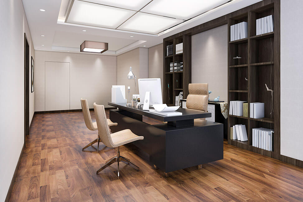 Modern office interior with dark wooden shelving, a sleek desk setup featuring two monitors, and comfortable chairs on a hardwood floor.