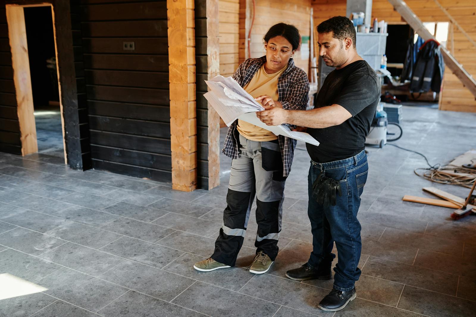 A Man and a Woman Holding a Paper While Standing on the Tiled Wall