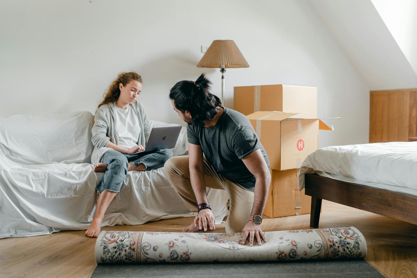 A couple relaxes while unpacking in their new apartment, creating a cozy home environment.