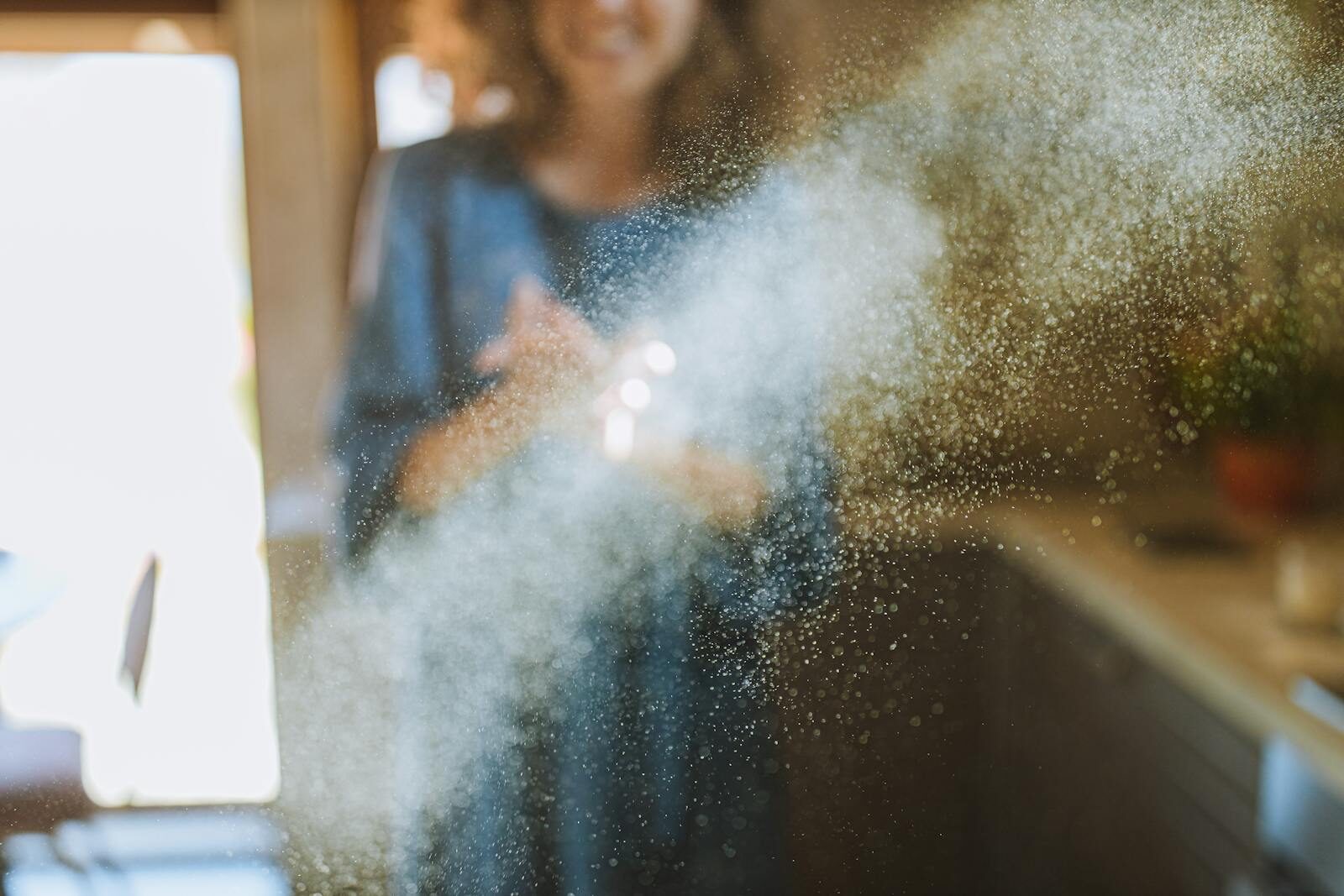 Sunlight cascades through the kitchen as flour dust illuminates in the air, creating a warm, inviting atmosphere.
