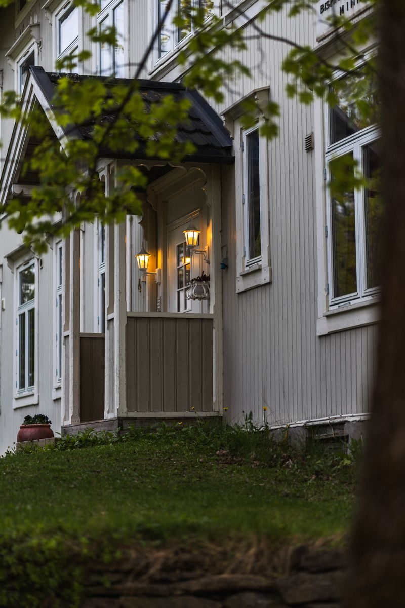 Cozy Scandinavian house with warm lights at twilight, showcasing classic wooden architecture.