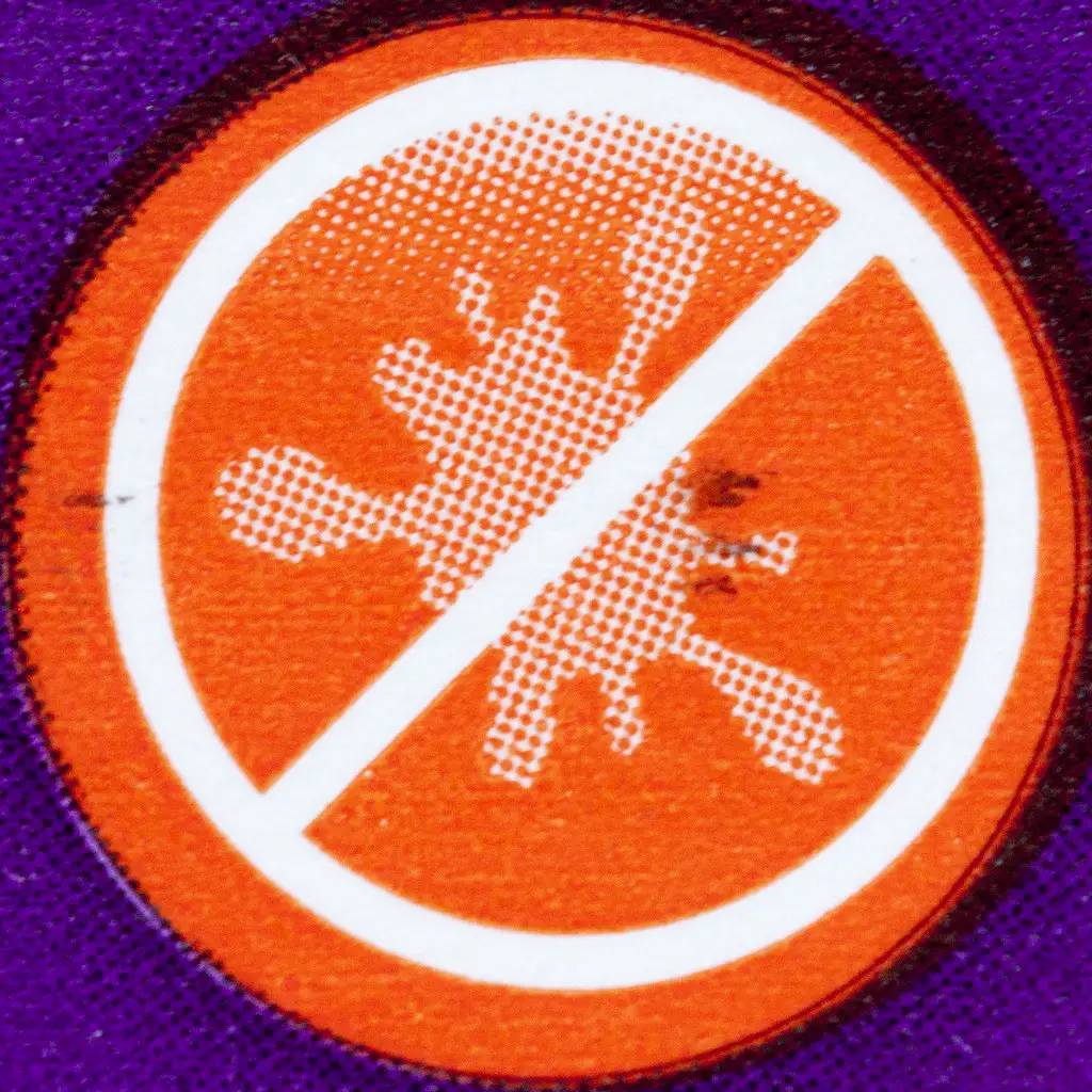 An orange circle with a white splash mark inside is crossed out by a diagonal line, symbolizing "no stains" on a purple background—a clear stain removal guide in icon form.