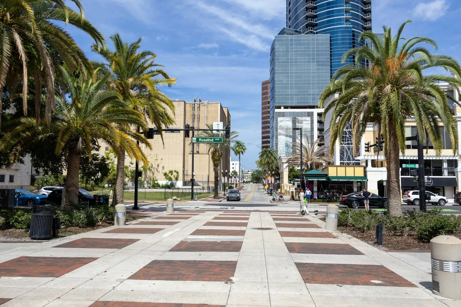 a city street with palm trees and buildings in the background